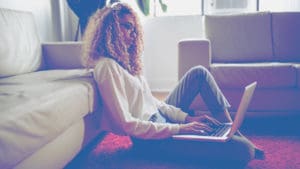 woman on floor typing laptop